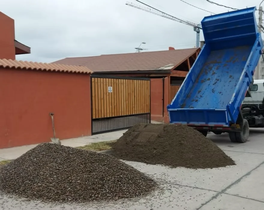 Camión tolva de CyJ descargando material frente a una casa